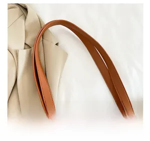 Detail showing the comfortable brown leather shoulder strap and woven straw texture