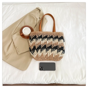Detail of color-block straw tote with woven texture and leather handles in summer setting