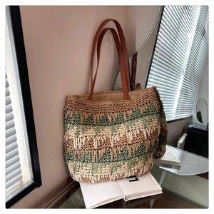 Detail of hand-woven straw tote with tri-color stripes and leather handles