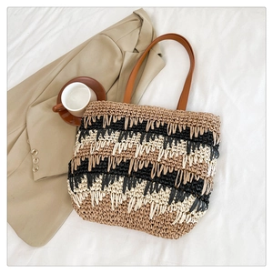 Detail of color-block straw tote with black and beige stripes and brown leather strap