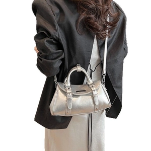 Silver metallic Boston bag with dual buckle details and top handle shown on model