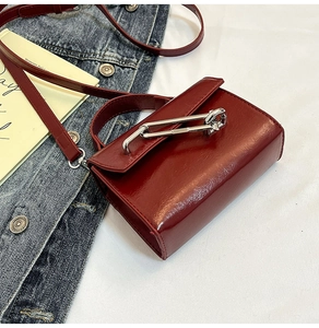 Détail du mini sac à main bordeaux brillant avec une boucle épingle de nourrice argentée