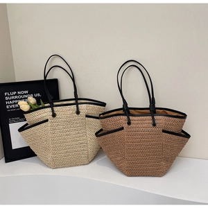 Dettaglio della borsa tote in paglia intrecciata con bordi neri e manici estivi