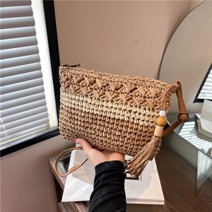Handmade straw shoulder bag with leather strap and tassel detail for summer beach vacations
