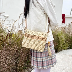 Straw woven crossbody bag with striped pattern and tassel detail for beach vacation