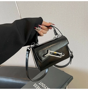 Détail d'un sac bandoulière en cuir brillant noir avec fermoir chaîne argenté unique