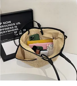 Dettaglio della grande borsa tote in paglia che mostra l'ampio interno per gli accessori