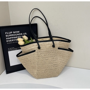 Dettaglio della borsa tote in paglia intrecciata con manici in pelle nera e tasche