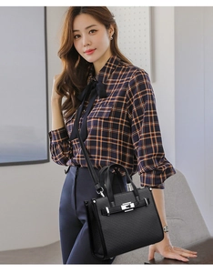 Detailed view of black textured leather bag with silver metal lock and buckle closure