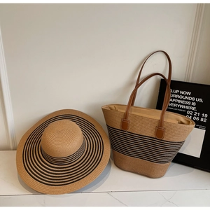 Striped straw tote bag and sun hat set with leather handles on marble surface