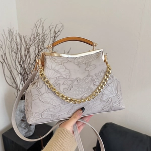 Vintage evening handbag with embossed koi and lotus pattern on a light grey textured surface