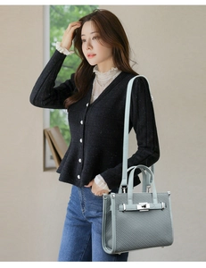Close-up of light blue lychee texture handbag with silver twist lock on knit cardigan