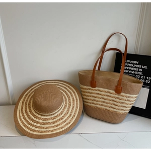 Detail of striped woven straw hat and tote bag set with brown leather handles