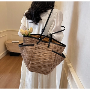 Dettaglio della grande borsa tote in paglia con finiture in pelle nera e tulipani