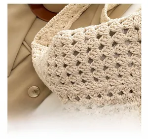 Detail of hand-woven crochet texture on cream tote bag with elegant shoulder strap