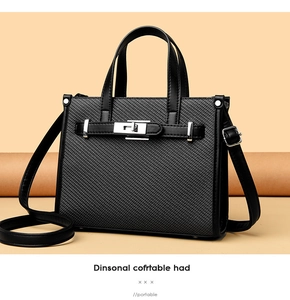 Detail of black woven texture leather bag with silver metal turn-lock and handle