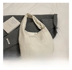 Dettaglio della borsa tote in velluto a coste bianco crema con texture e bottone a scatto