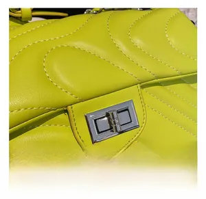 Detail of silver twist lock and wavy quilted stitching on neon green crossbody bag