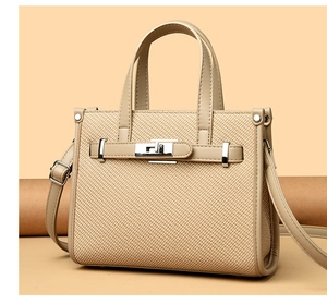 Detailed view of beige textured handbag with silver buckle and adjustable shoulder strap