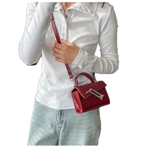 Sac carré moderne rouge brillant avec fermoir barre argentée porté par un modèle