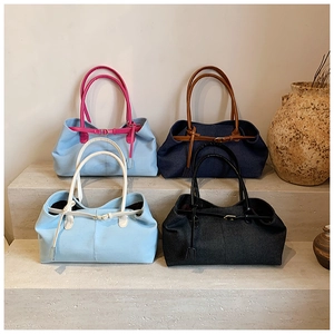 Détail de sacs fourre-tout contrastés en denim et toile sur des marches en pierre
