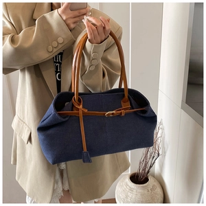 Détail du sac cabas en denim bleu avec anses en cuir marron et boucle en métal contrastée