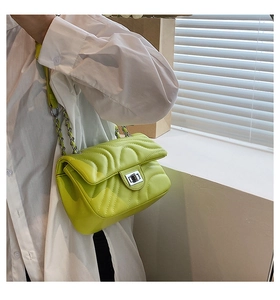 Close-up of lime green quilted crossbody bag with silver twist lock and chain strap