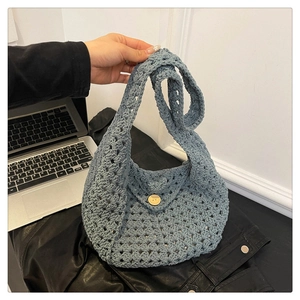 Detailed macro view of blue hand-woven tote bag with flower pattern and wooden button
