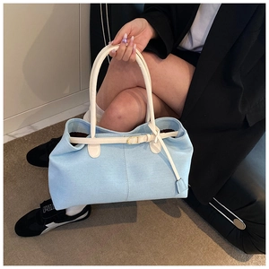 Détail du sac cabas en denim bleu avec anses en cuir crème et boucle métallique décorative