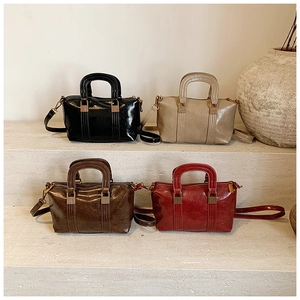 Boston bags in black, beige, brown, and burgundy colors displayed on stone steps