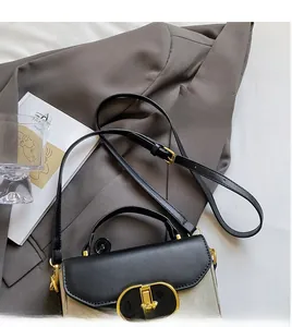 Detail of a vintage box crossbody bag with a gold metal clasp and smooth long shoulder strap