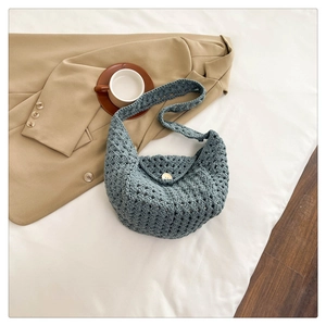 Macro detail of hand-woven grey-blue crochet bag with wooden button and knit texture