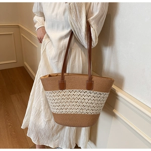 Detail of hand-woven striped straw tote bag featuring leather straps and mesh texture
