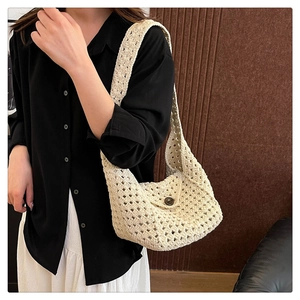 Close-up of cream white crochet handbag with woven texture and vintage brown button detail