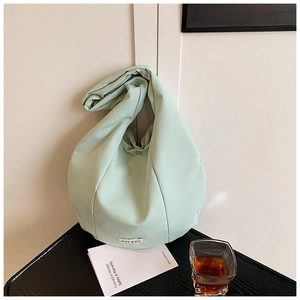 Dettaglio della borsa tote in velluto a coste verde menta con chiusura a scatto ed etichetta