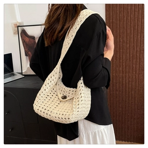 Close-up of cream woven shoulder bag with button detail on a model in a natural setting