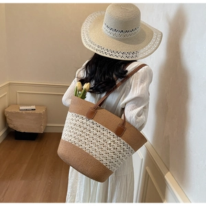 Matching set of large striped straw tote bag and hollow knit sun hat for beach travel