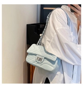 Close-up of light blue chain bag with wave quilting and silver rotary metal lock