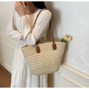 Detail of hand-woven straw tote bag with brown leather handles and striped texture
