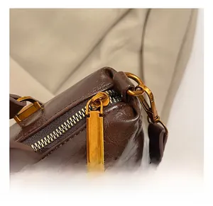 Detail of vintage coffee leather handbag with gold zipper hardware and precise stitching
