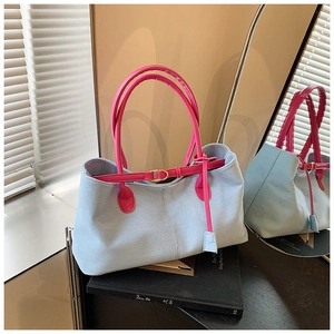 Détail des poignées en cuir rose contrastées sur le sac cabas en denim bleu clair