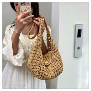 Detail of hand-woven straw shoulder bag featuring an elegant circular wooden buckle closure