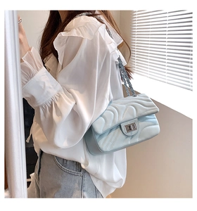 Detailed view of light blue quilted leather texture and silver clasp on a small square bag