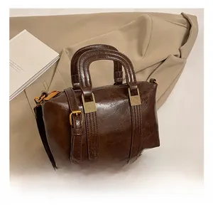 Detailed view of dark brown vintage leather handbag with textured gold metal hardware