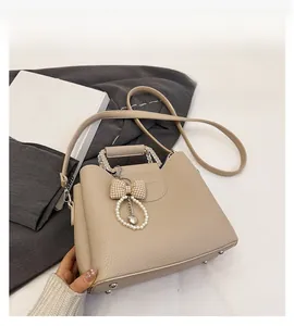 Detail of apricot lychee leather bag with pearl chain handle and bow accessory