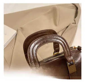 Detail of vintage brown leather handbag with reinforced handle and matte gold hardware