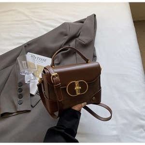 Detailed shot of brown vintage crossbody bag with gold buckle on white bedding