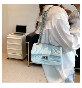 Close-up of light blue quilted crossbody bag with silver buckle and chain strap on model
