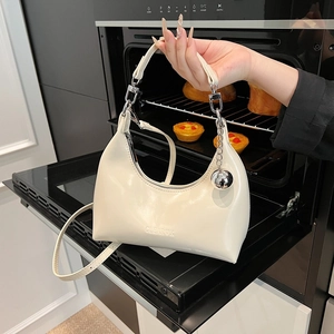 Détail du sac croissant crème avec ferrures argentées et logo gravé sur le cuir