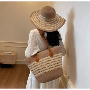 Detail of hand-woven straw tote bag and matching wide-brim hat with brown leather handles